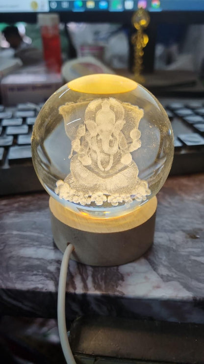 Ganesh Crystal LED Lamp - Shoppingstore25Shoppingstore258121759318The Ganesh Crystal LED Lamp features an etched image of Lord Ganesha on a lit wooden base, placed in front of a computer keyboard and monitor with a white cable attached.