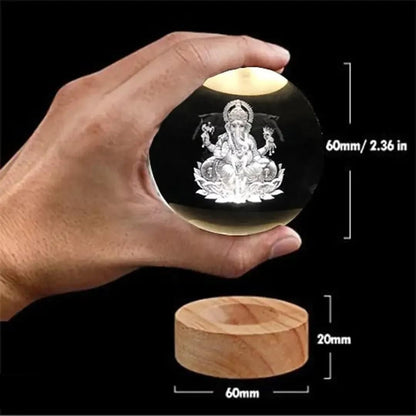 Ganesh Crystal LED Lamp - Shoppingstore25Shoppingstore258121759318A hand holds the Ganesh Crystal LED Lamp, featuring a 60mm diameter crystal - glass orb with an etched Lord Ganesha inside, resting on a wooden base measuring 20mm tall and 60mm wide.